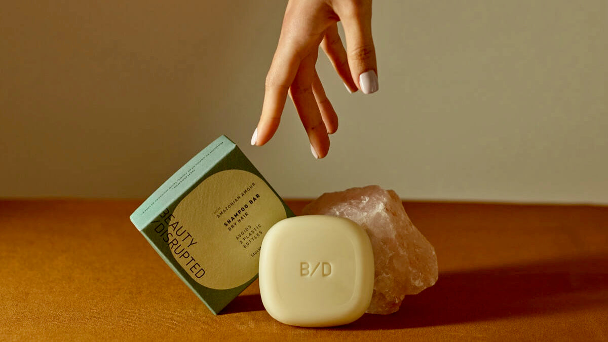 Beauty Disrupted Amazonian Amour solid shampoo bar on a white stone holder in a minimalist bathroom setting, showcasing plastic-free and pH-balanced hair care.