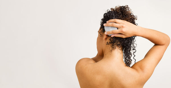 A woman in a shower holding a Beauty Disrupted bar, emphasizing the high-performance and sensory experience of the solid ritual.