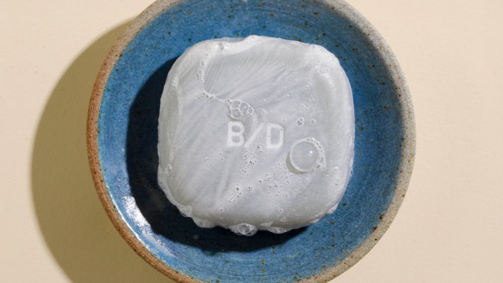 Beauty Disrupted solid Conditioner & Mask covered in dense white lather, resting in a handmade blue ceramic dish — zero plastic, crafted in the South of France